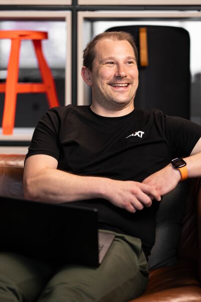 tech employee smiling on couch with laptop and smart watch