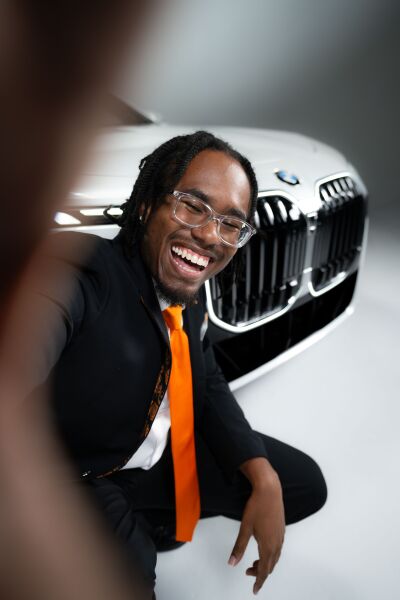 RSA smiling in front of car holding camera
