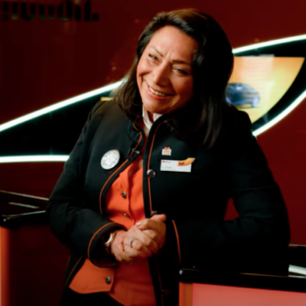 A Rental Sales Agent in her SIXT uniform stands smiling in a SIXT branch.