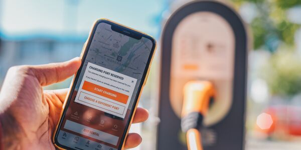 A close-up using the SIXT mobile app to reserve a charging port at an electric vehicle charging station, illustrating the infrastructure.
