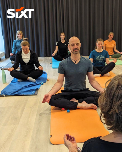 A group of people sitting cross-legged on yoga mats, meditating peacefully.