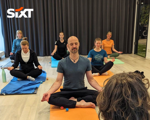 A group of people sitting cross-legged on yoga mats, meditating peacefully.