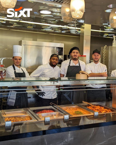Five men in chef uniforms standing together in the kitchen.