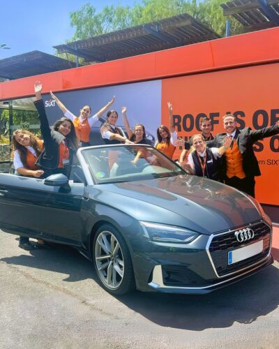 The Sixt Tenerife operations team standing in front of a Sixt rental vehicle outside a branch.