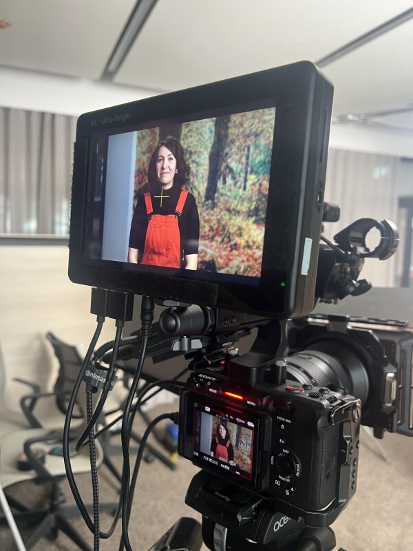A camera captures a smiling woman working at SIXT TECH.